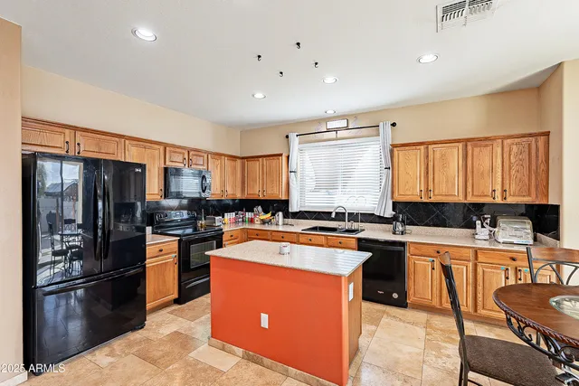 a kitchen with stainless steel appliances a refrigerator a sink a stove a table and chairs