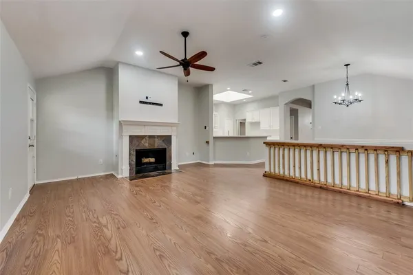 a view of an empty room with wooden floor fireplace and a window
