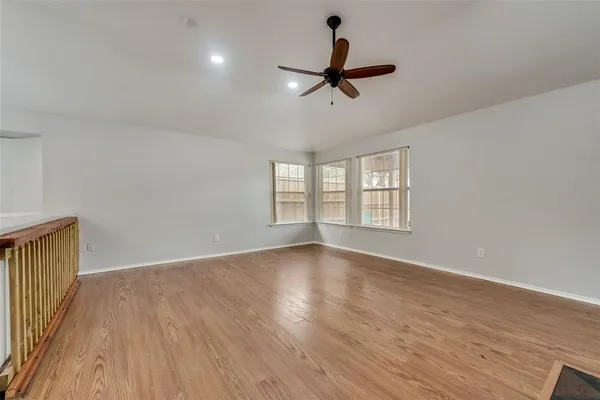 a view of empty room with wooden floor and fan