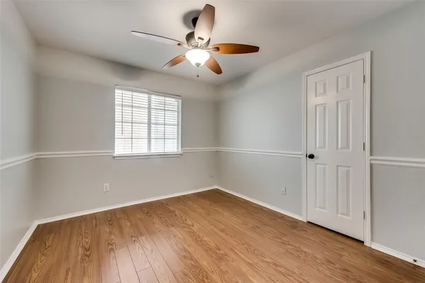 an empty room with wooden floor fan and windows