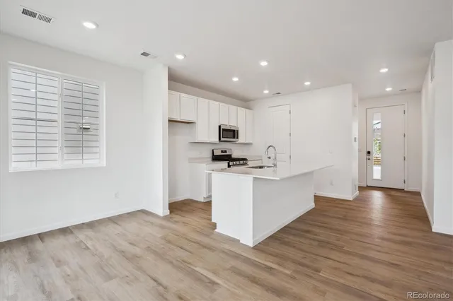 a kitchen with stainless steel appliances granite countertop a stove top oven a sink and a refrigerator