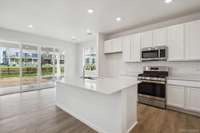 a kitchen with stainless steel appliances granite countertop a stove a sink and a microwave