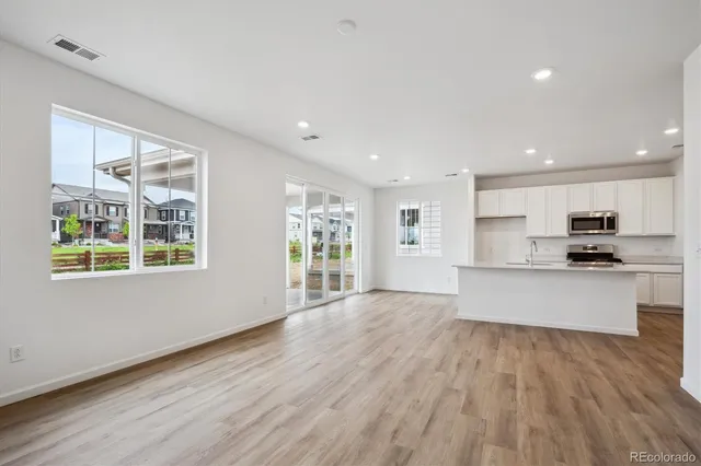 a large open kitchen with kitchen island granite countertop a stove top oven a sink and a large window