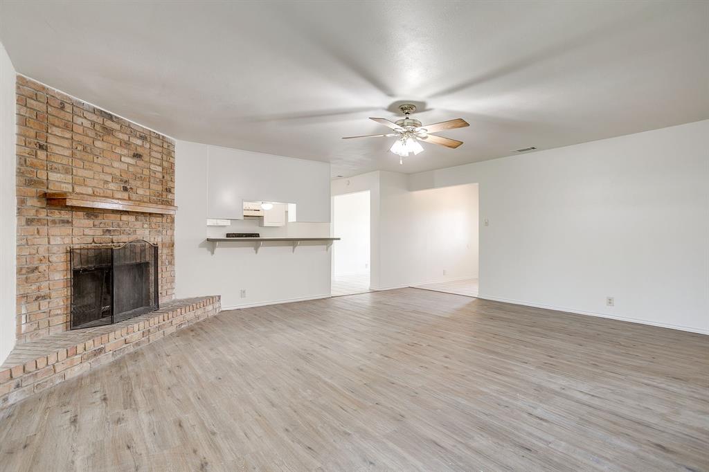1203 North Nolan River Road, Unit A Cleburne, TX 76033 - Photo 11 of 20 wooden floor in an empty room with a fireplace