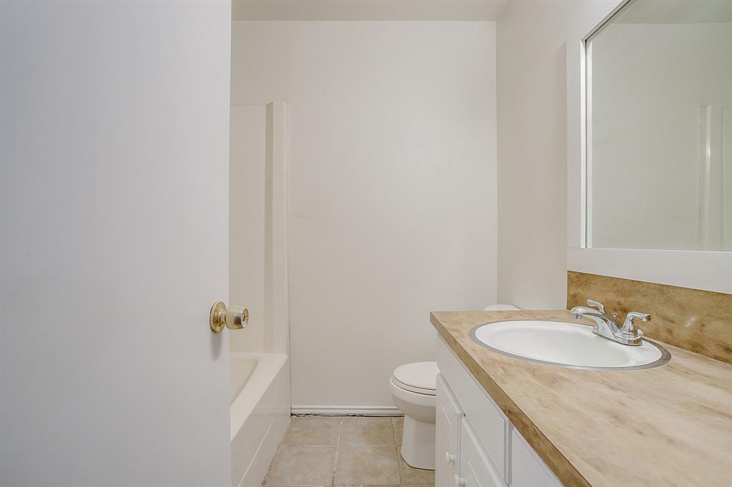1203 North Nolan River Road, Unit A Cleburne, TX 76033 - Photo 17 of 20 a bathroom with a granite countertop sink toilet and a mirror