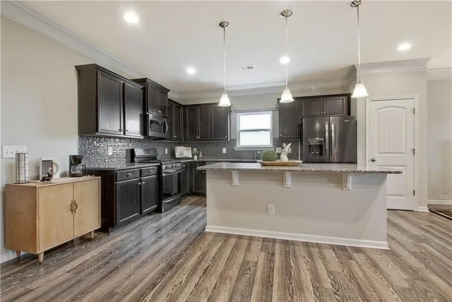 a large kitchen with stainless steel appliances granite countertop a stove a sink dishwasher and a refrigerator with wooden floor