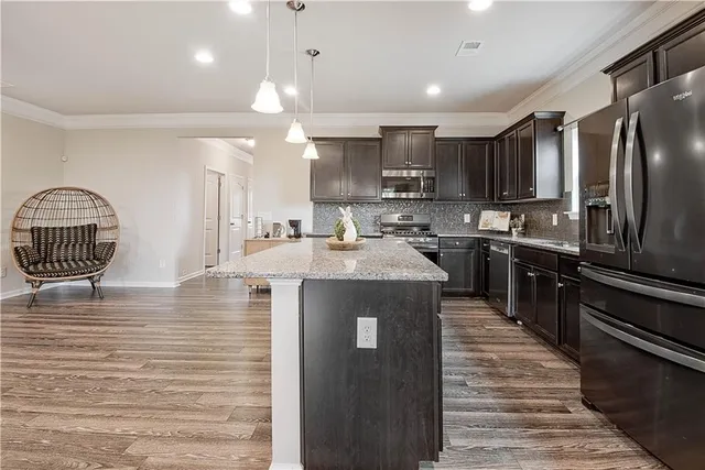 a kitchen with kitchen island granite countertop a stove top oven a sink dishwasher a dining table and chairs with wooden floor