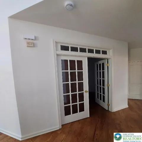 a view of an empty room with wooden floor and windows