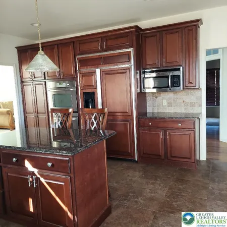 a kitchen with stainless steel appliances granite countertop a refrigerator a stove and a sink with wooden floor
