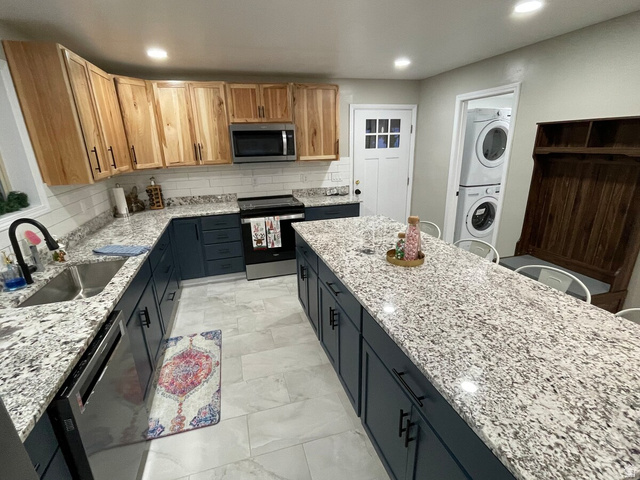 2807 North Ogden Canyon Road Eden, UT 84310 - Photo 10 of 72 Spacious kitchen featuring a large central island, granite countertops, and two-tone cabinetry with natural wood-finish uppers and dark blue lowers