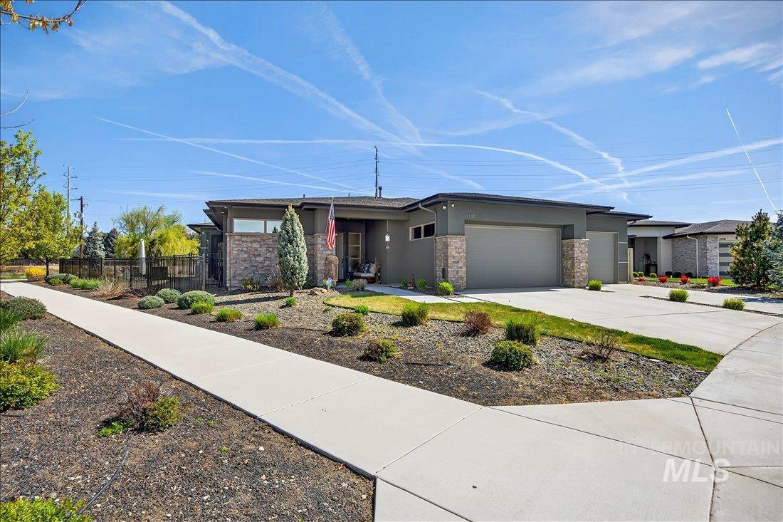 4718 East Goldstone Drive Meridian, ID 83642 - Photo 1 of 50 Prairie-style house featuring stucco siding, a garage, driveway, and stone siding