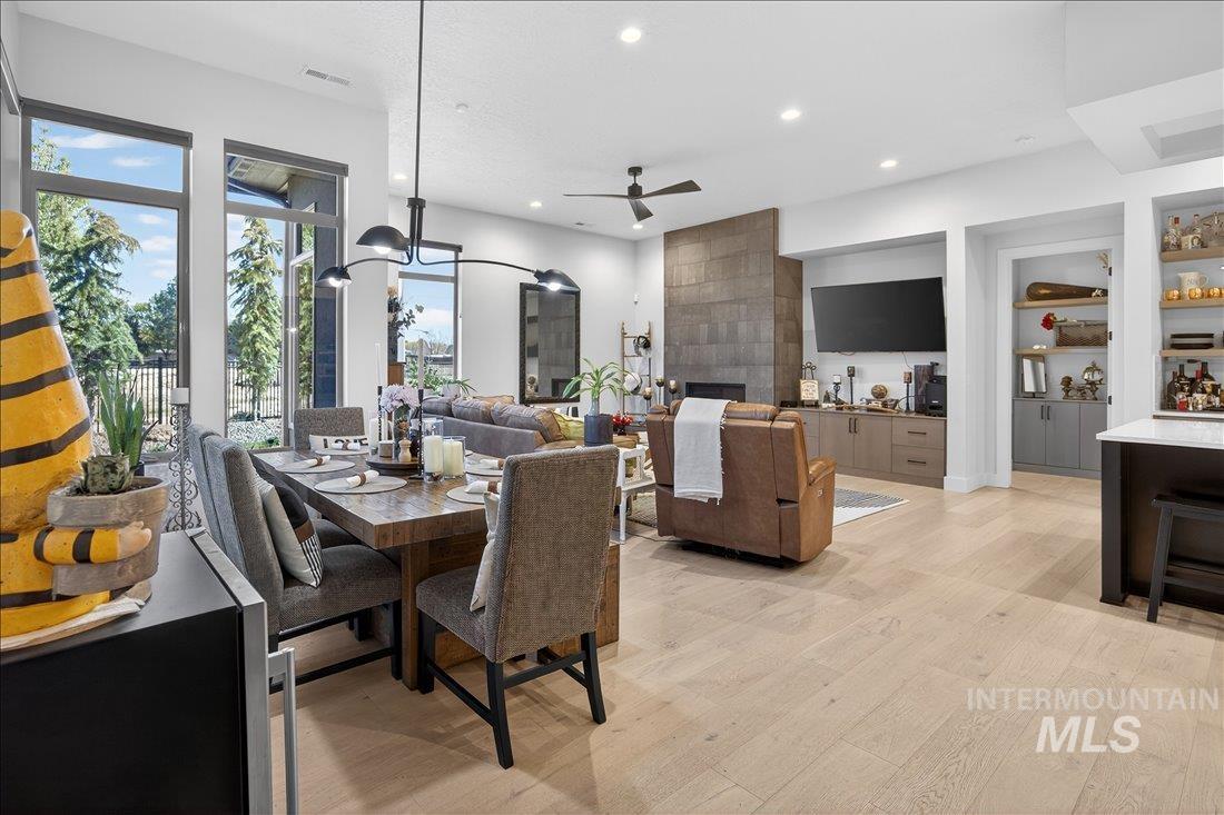 4718 East Goldstone Drive Meridian, ID 83642 - Photo 16 of 50 Dining space with light wood-style flooring, built in features, a tiled fireplace, recessed lighting, and a ceiling fan