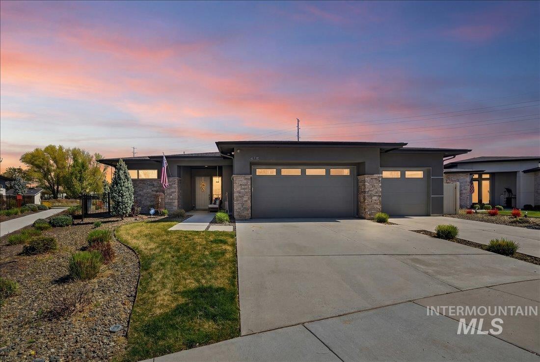 4718 East Goldstone Drive Meridian, ID 83642 - Photo 2 of 50 Prairie-style house with a garage, concrete driveway, stone siding, stucco siding, and a yard