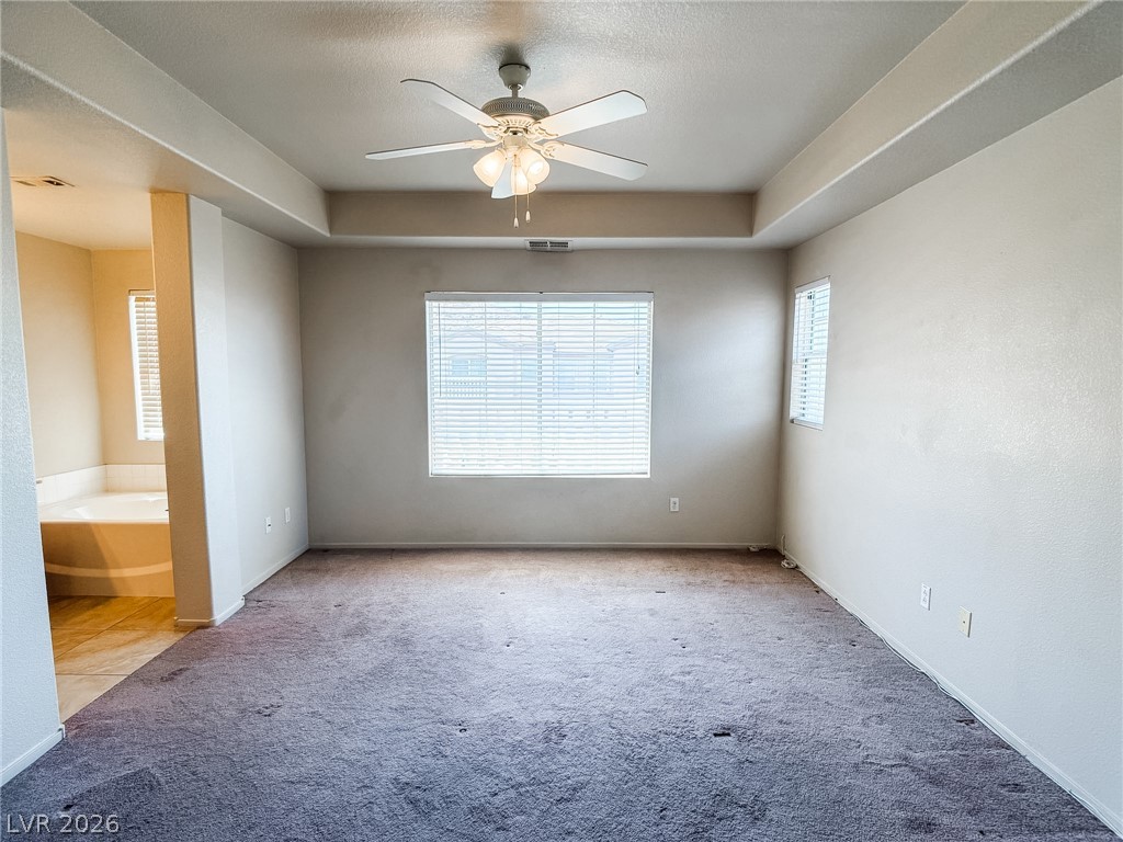 228 Positive Point Street Henderson, NV 89012 - Photo 14 of 27 A spacious primary bedroom features tray ceilings, a cooling ceiling fan, and ample window light.