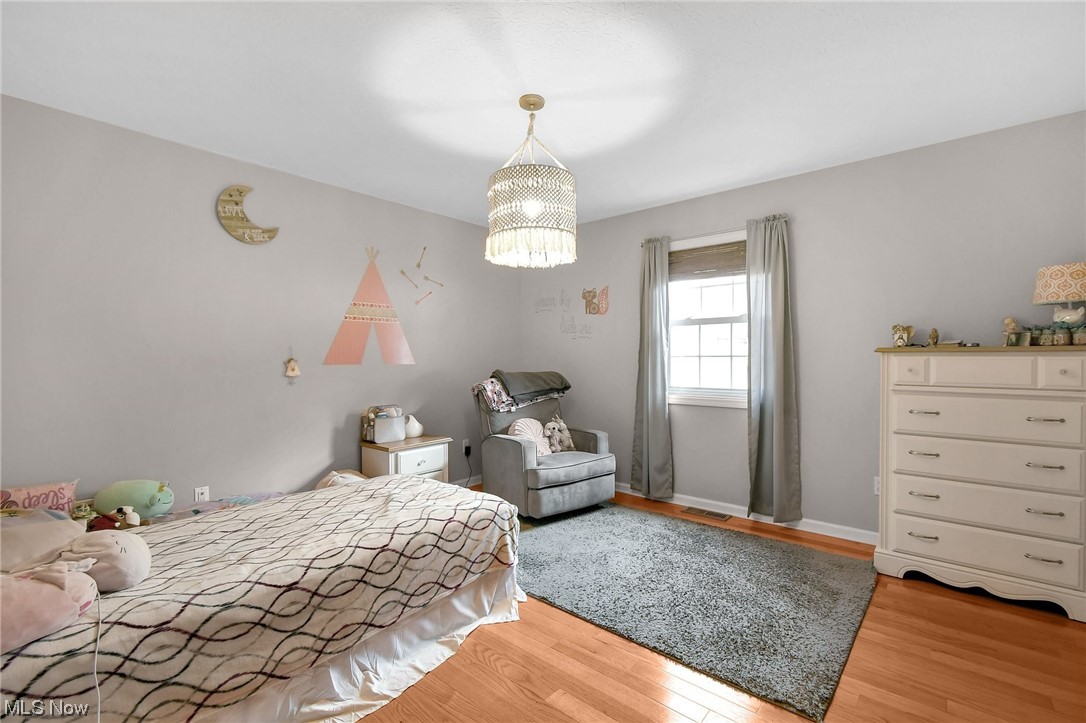 4900 Ellerman Road Zanesville, OH 43701 - Photo 14 of 28 Bedroom featuring a notable chandelier and light hardwood / wood-style floors