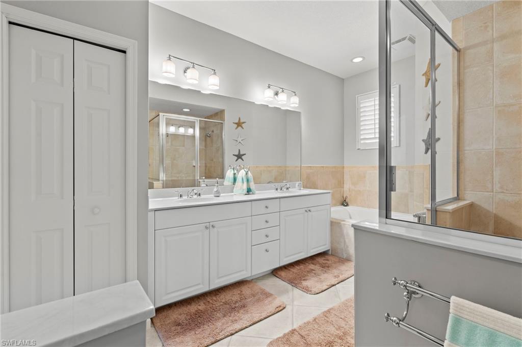 10422 Autumn Breeze Drive, Unit 201 Estero, FL 34135 - Photo 20 of 34 a bathroom with a double vanity sink a mirror and a bathtub