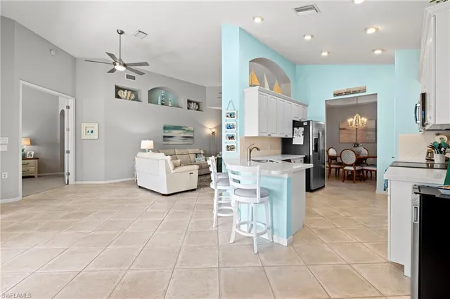 a large white kitchen with a sink and living room view