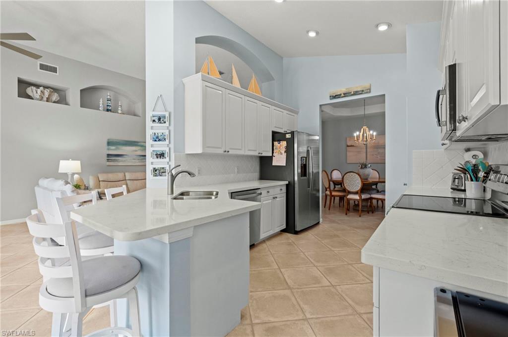 10422 Autumn Breeze Drive, Unit 201 Estero, FL 34135 - Photo 10 of 34 a large white kitchen with a sink and living room view