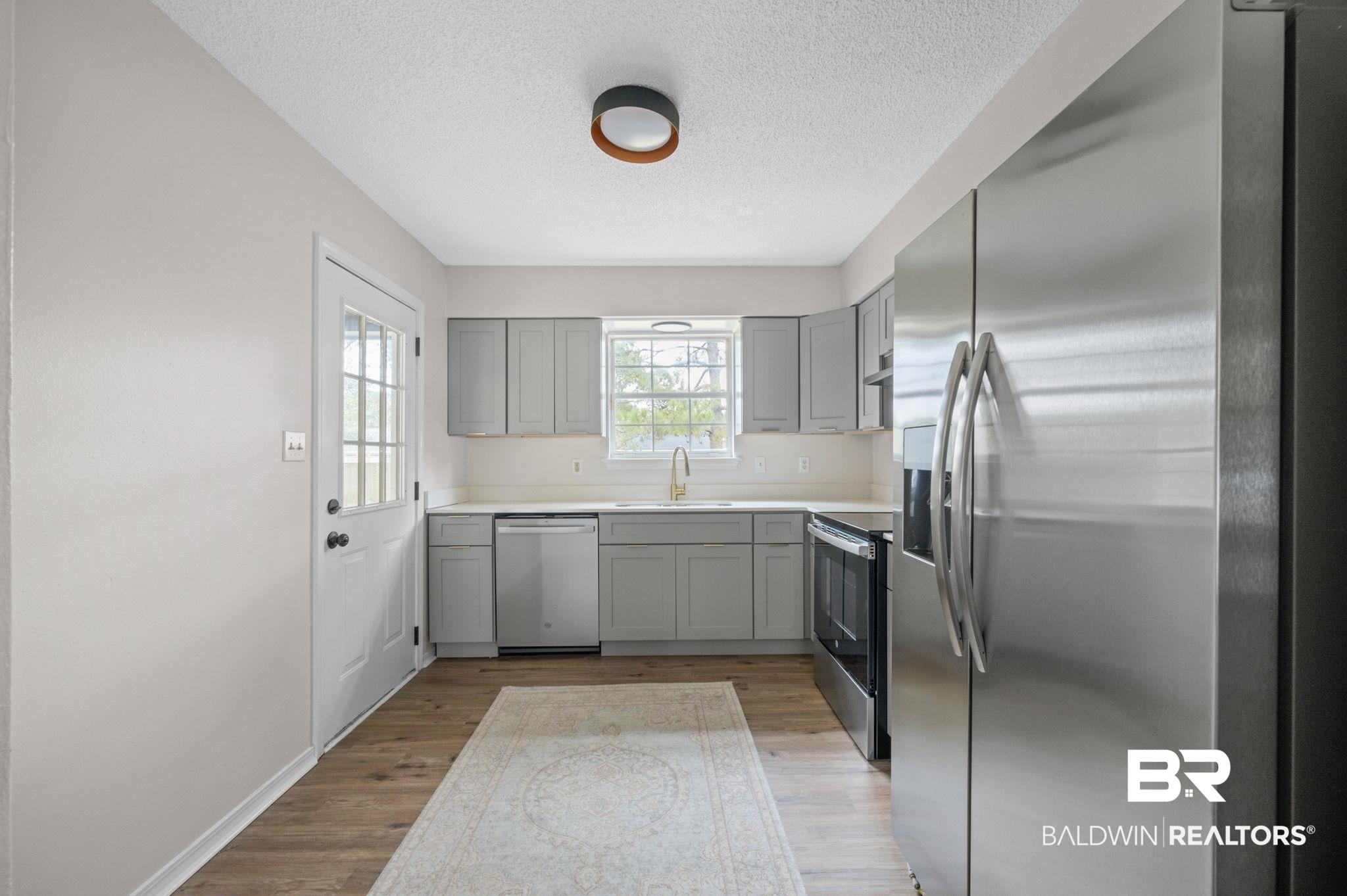 811 East Verbena Avenue Foley, AL 36535 - Photo 3 of 16 Kitchen featuring appliances with stainless steel finishes, light wood-type flooring, gray cabinetry, a textured ceiling, and sink