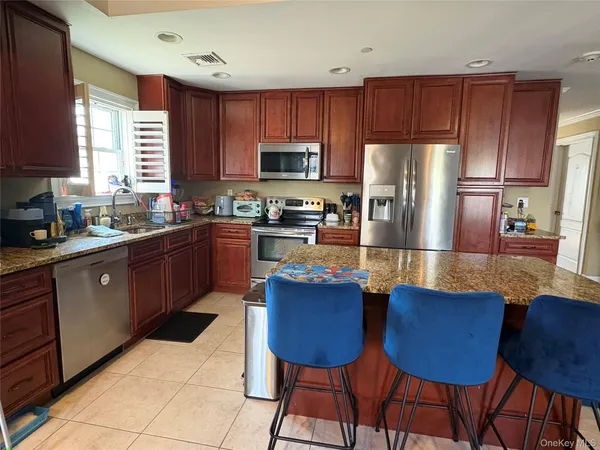 a kitchen with stainless steel appliances granite countertop a sink a stove a refrigerator a table and chairs