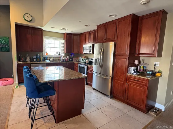 a kitchen with stainless steel appliances granite countertop a refrigerator a sink a stove a dining table and chairs