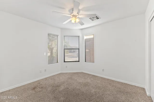 an empty room with windows and chandelier fan