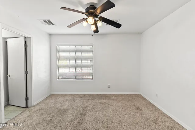 an empty room with a window and a fan