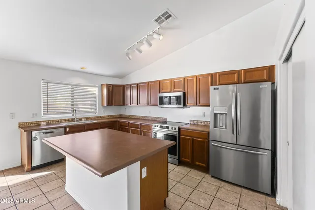 a kitchen with stainless steel appliances granite countertop a sink a stove and refrigerator