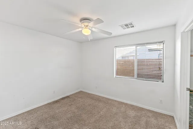 an empty room with windows and fan
