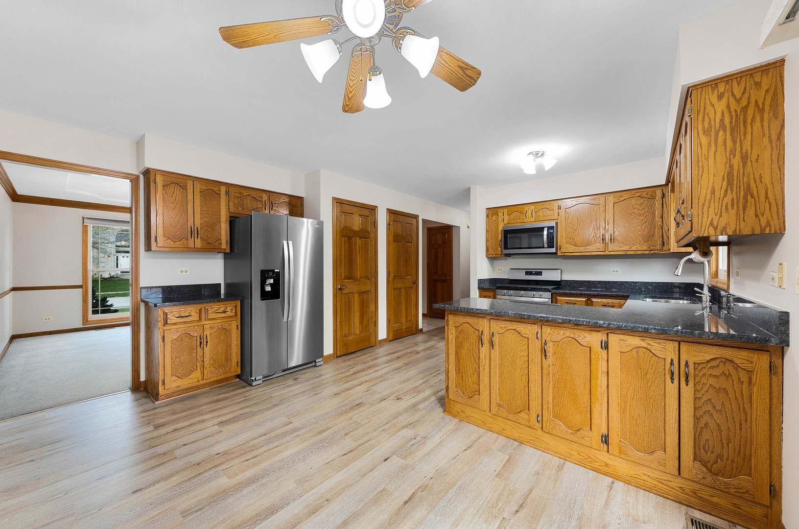 1751 Mundelein Road Naperville, IL 60565 - Photo 11 of 37 a kitchen with stainless steel appliances granite countertop a refrigerator a stove top oven a chimney wooden floor and cabinets