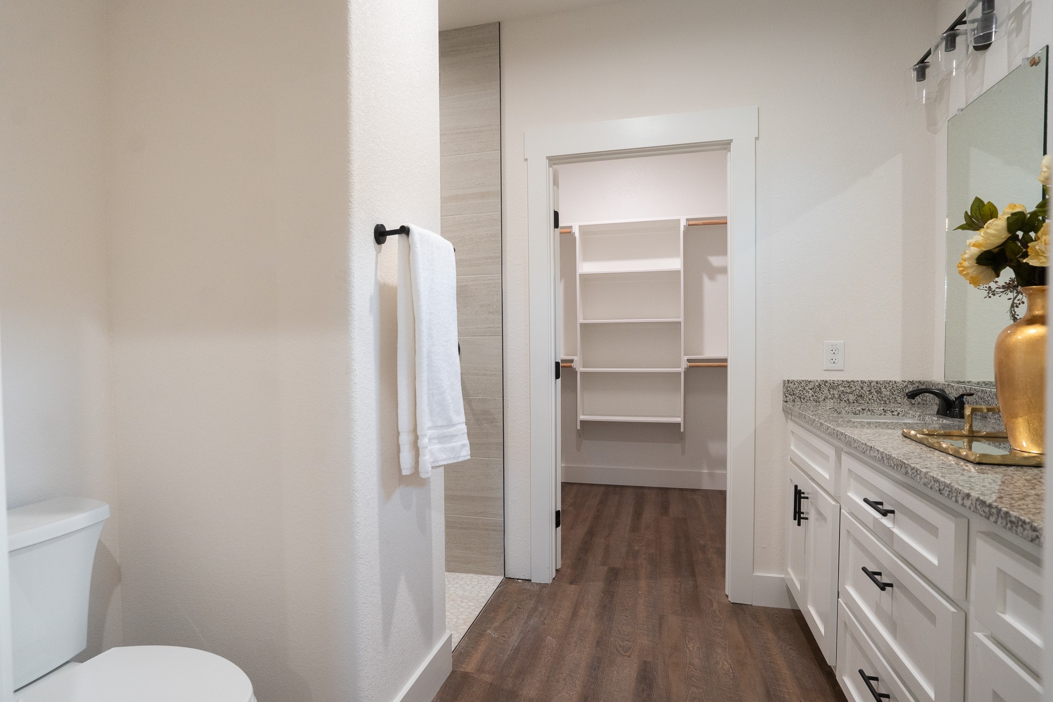 304 String Prairie Way Smithville, TX 78957 - Photo 22 of 30 Bathroom with wood finished floors, vanity, toilet, a spacious closet, and baseboards