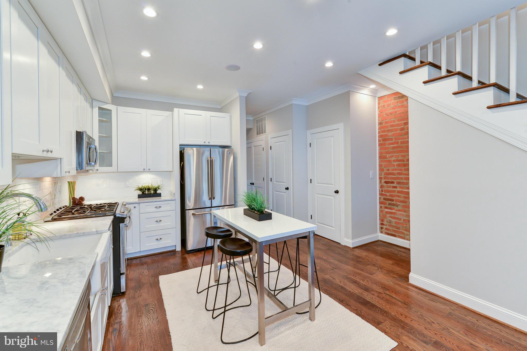 39 U Street Northeast, Unit 1 Washington, DC 20002 - Photo 9 of 27 a kitchen with stainless steel appliances kitchen island granite countertop a stove a refrigerator a sink a dining table and chairs with wooden floor