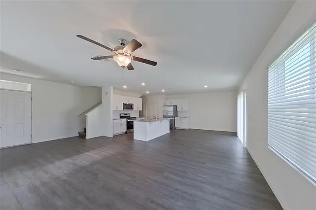 a view of empty room with wooden floor and ceiling fan