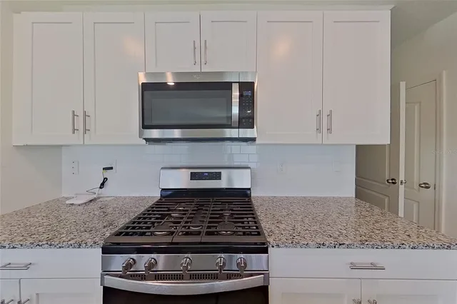 a kitchen with white cabinets and a stove