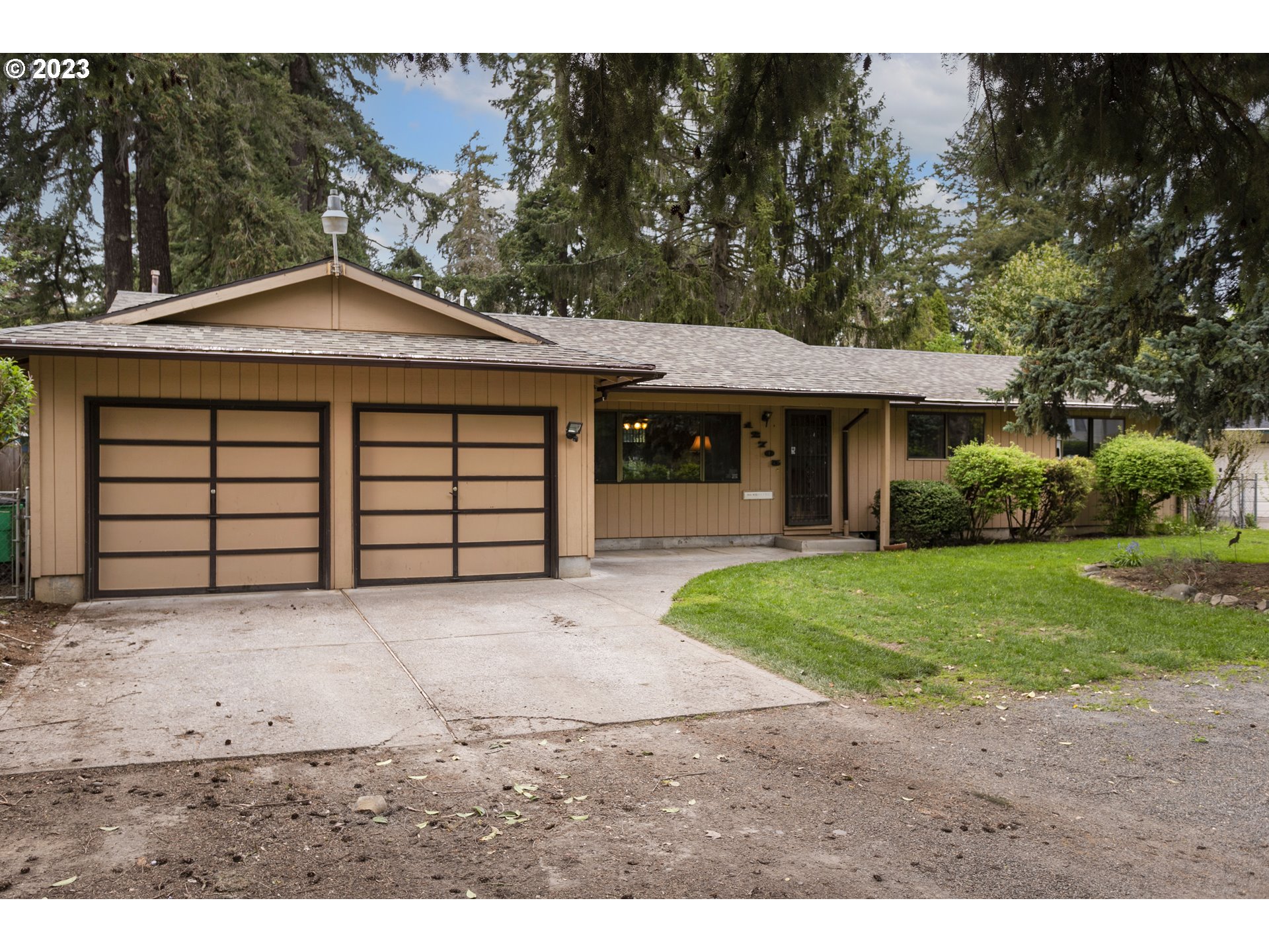 a front view of a house with a garden and trees