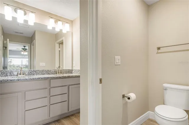 a bathroom with a granite countertop sink a toilet and a mirror
