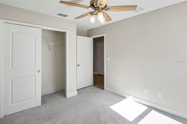 an empty room with a ceiling fan and a window