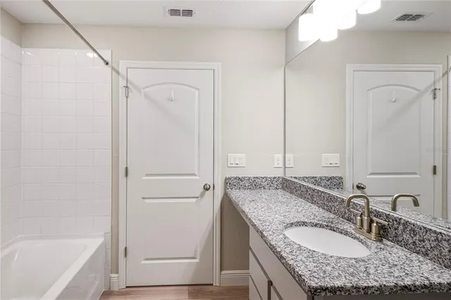 a bathroom with a granite countertop sink a mirror and a bathtub