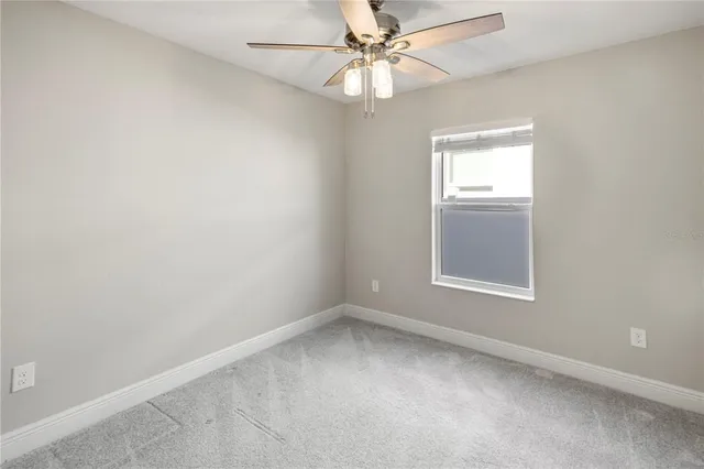 an empty room with a window and ceiling fan