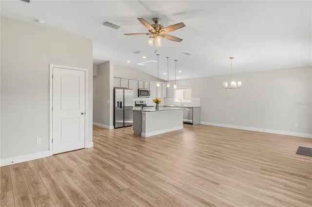 a view of an empty room with wooden floor and a ceiling fan