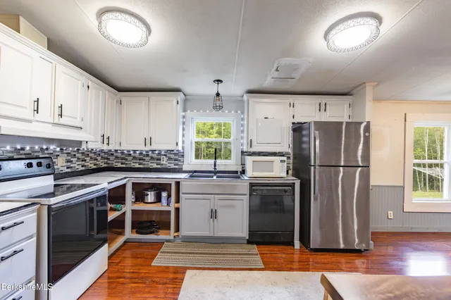 a kitchen with stainless steel appliances granite countertop a refrigerator a stove a sink and a microwave