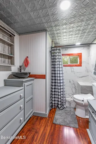 a view of an empty room with wooden floor and a bathroom