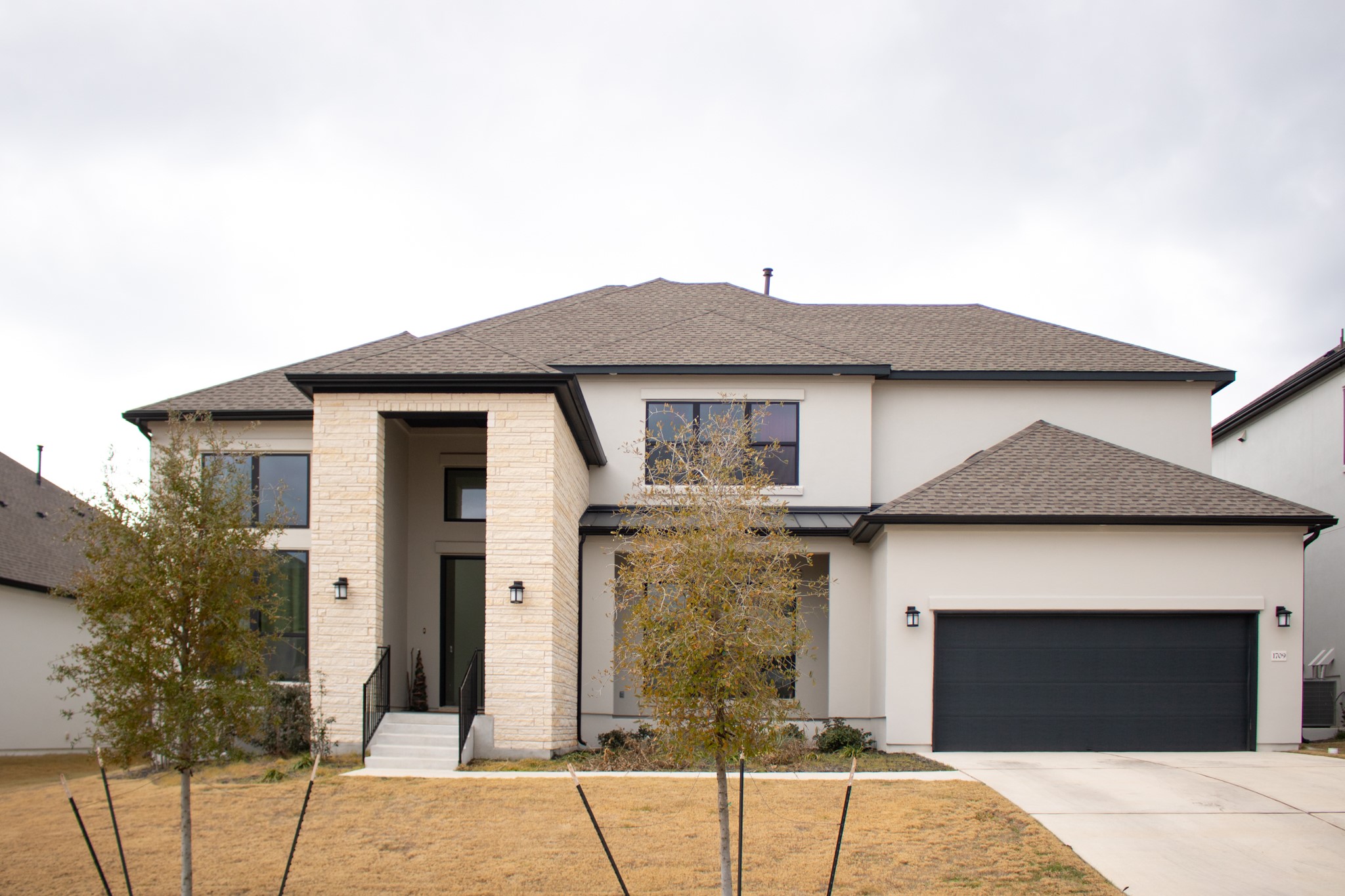 View of front of house with roof with shingles, stucco siding, driveway, and an attached garage