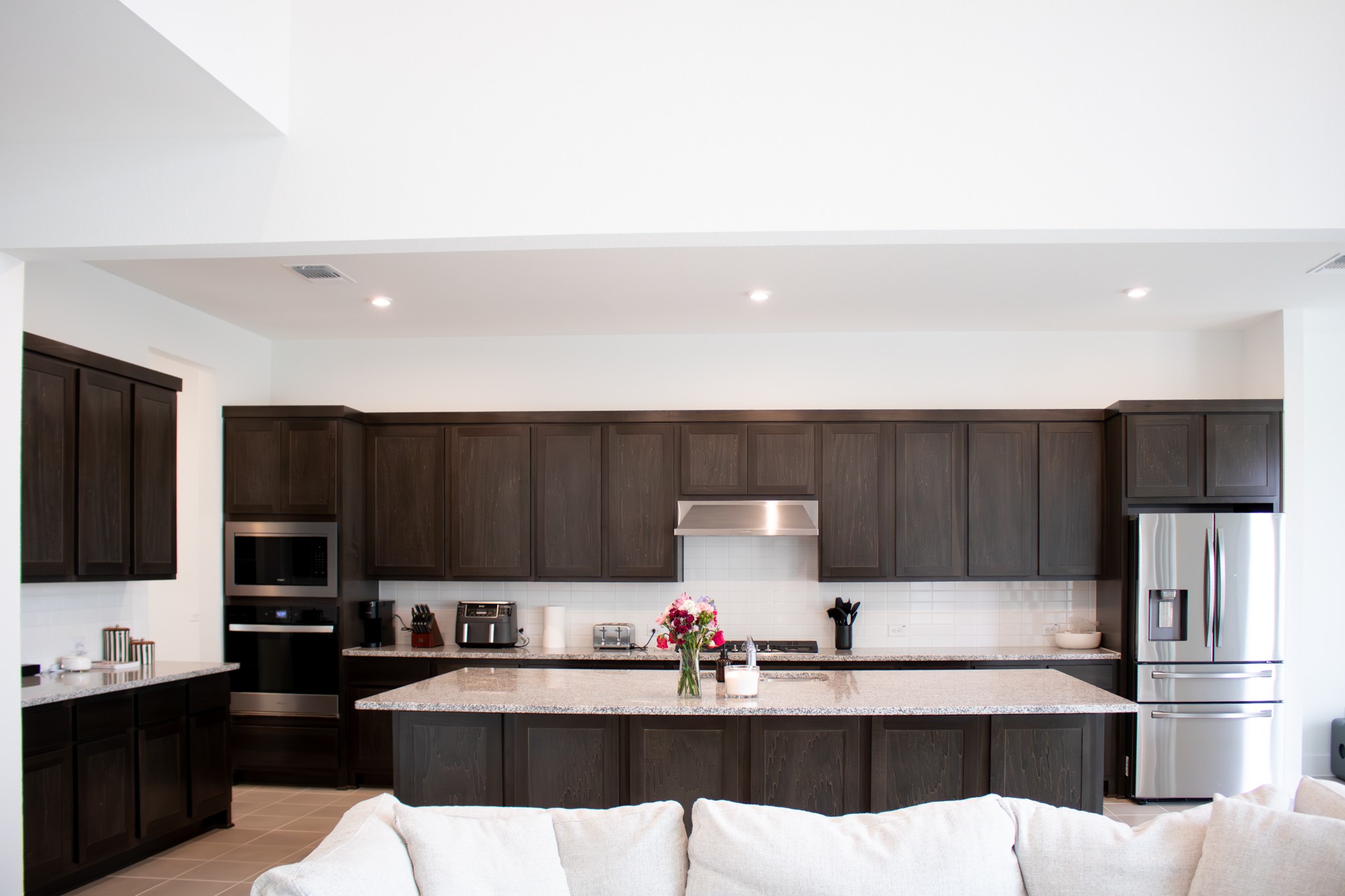 1709 Novara Trail Leander, TX 78641 - Photo 17 of 40 Kitchen featuring stainless steel appliances, an island with sink, dark wood finish cabinets, light stone countertops, and recessed lighting
