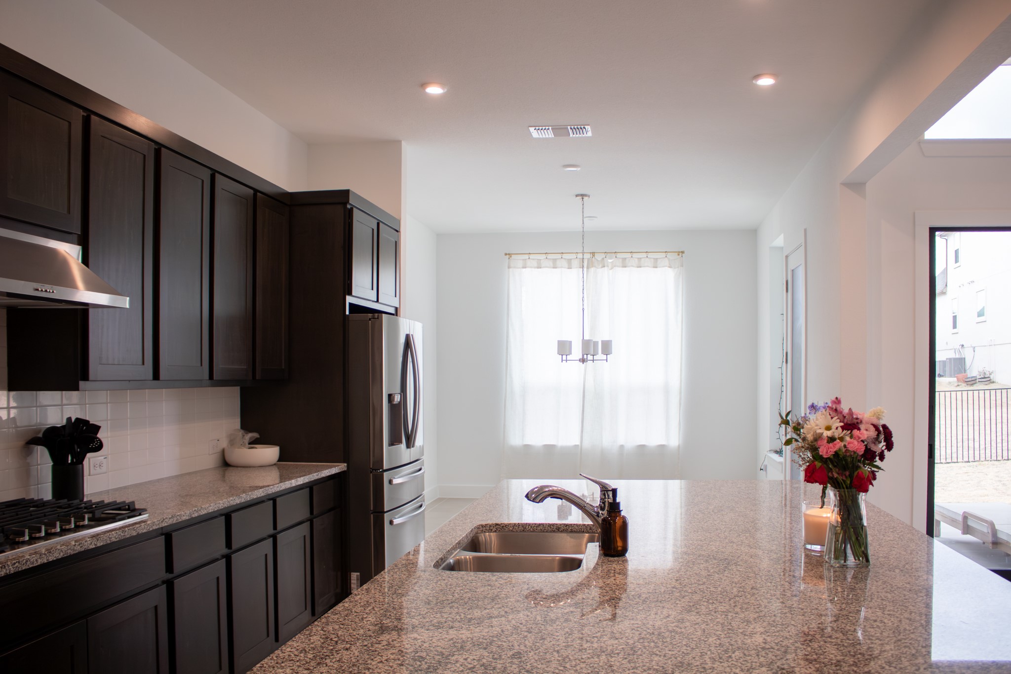 1709 Novara Trail Leander, TX 78641 - Photo 18 of 40 Kitchen with light stone countertops, stainless steel appliances, decorative backsplash, recessed lighting, and dark wood finish cabinetry