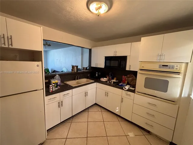 a kitchen with granite countertop white cabinets and black appliances