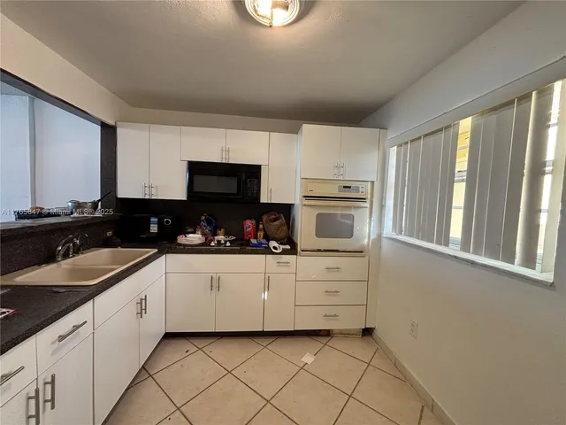 a kitchen with granite countertop white cabinets and white appliances
