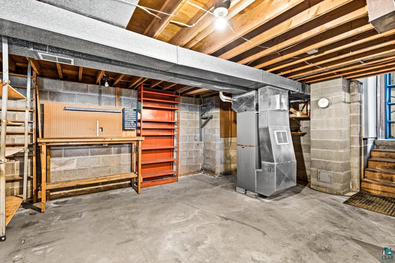 6606 Metso Road Kettle River, MN 55757 - Photo 84 of 84 Unfinished basement with concrete flooring, exposed ceiling joists, concrete block walls, utility systems, and a built-in workbench with shelving