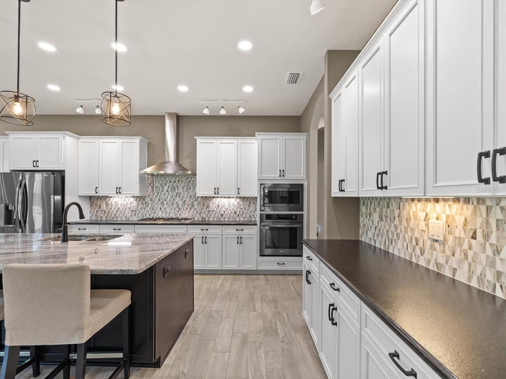 11981 Robina Road Weeki Wachee, FL 34614 - Photo 11 of 93 a large kitchen with granite countertop lots of counter space white cabinets and stainless steel appliances