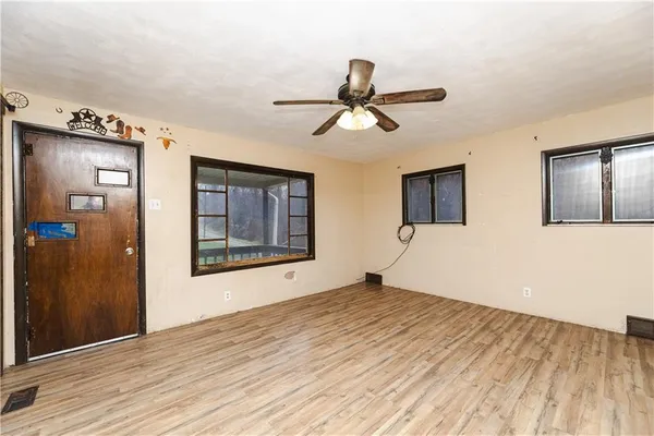 a view of an empty room with wooden floor and a window
